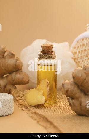 Bottiglia di vetro di olio essenziale di zenzero, radice di zenzero su sfondo beige. Vita alternativa sana. Massaggio olio organico toni della terra cosmetici naturali i Foto Stock