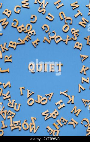 Parola TRANQUILLA fatta di lettere di legno su sfondo blu chiaro. Concetto di citazioni di parole motivazionali. Frase di ispirazione Foto Stock