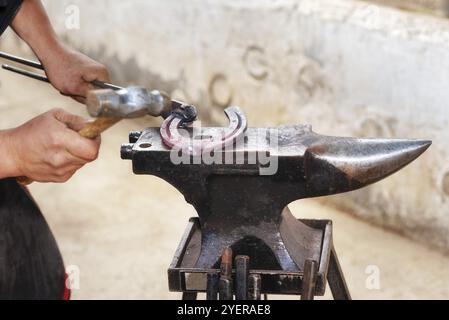 Fabbro che lavora all'incudine, che fa un ferro di cavallo Foto Stock