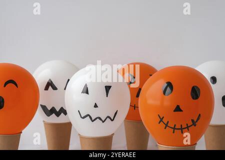 La faccia di Jack dipinta sulle bollature. Preparazione di palline bianche e arancioni fai da te per la festa di Halloween. Halloween attività a casa. Giocattoli fatti a mano Artigianato per bambini Foto Stock