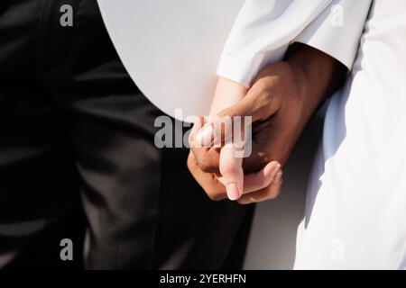 coppia romantica che si tiene per mano alla luce del sole, sposo bianco e nero sposo sposa sposa sposa sposa sposa sposa, mani di diverse razze Foto Stock