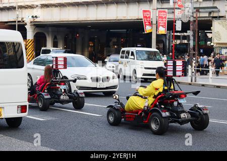 TOKYO, GIAPPONE - 31 ottobre 2024: I turisti guidano go-cart a noleggio nella zona di Ueno a Tokyo. Una bandiera su un lampione pubblicizza una mostra di Hello Kitty. Foto Stock