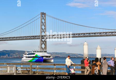 Persone in attesa in coda per il servizio di traghetto carina che arriva all'edificio del centro e al Bay Bridge San Francisco California USA Foto Stock