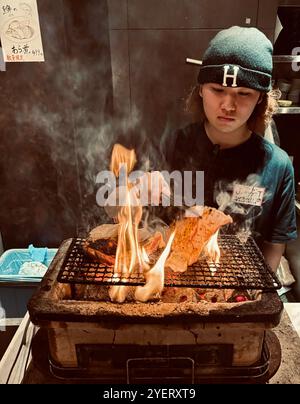 Un giovane giapponese che grigia spiedini al ristorante Washio Yakitori Izakaya a Chuocho, Kagoshima, Giappone. Foto Stock