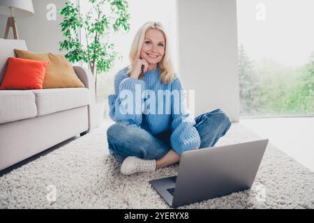 Ritratto a tutto il corpo di una signora anziana seduto per il passatempo del laptop fine settimana interni bianchi in casa Foto Stock