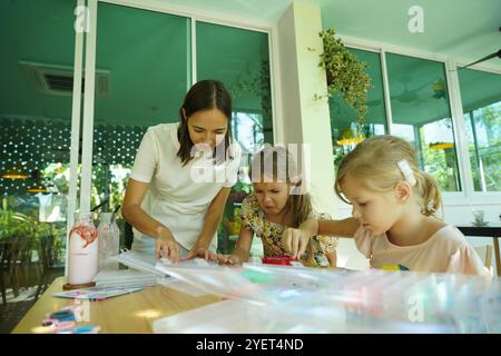 L'insegnante in officina ha messo in tecnica due ragazze come assemblare un mosaico termico Foto Stock