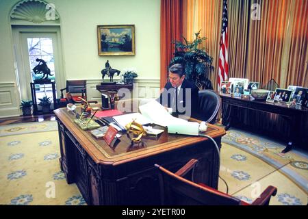 Il presidente Ronald Reagan lavora alla sua scrivania nell'ufficio ovale. noye gli accessi mi hanno dato per partecipare ad un minuto di progetto nella vita del mondo. Fotografia di Dennis Brack BB87 foto di Dennis Brack Foto Stock