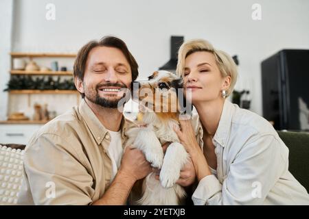 Una coppia si abbraccia l'un l'altro e il suo cane, irradiando l'amore in un'atmosfera allegra. Foto Stock