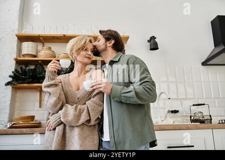 Una coppia condivide un momento tenero sul caffè, abbracciando calorosamente nella loro elegante cucina. Foto Stock