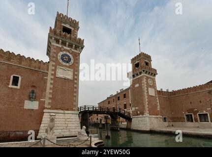 Venezia, vento - IT - 13 ottobre 2024 l'Arsenale di Venezia presenta pareti in mattoni rossi, porte ad arco e torreggianti torri di guardia. All'interno, vasti magazzini aperti Foto Stock