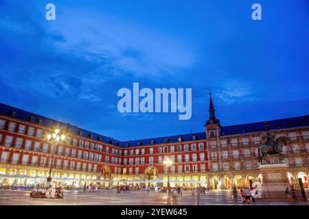 La vivace Plaza Mayor di Madrid, in Spagna, illuminata al crepuscolo con la sua architettura iconica, le luci vivaci e i visitatori che si godono la piazza storica. Foto Stock