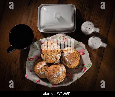 Classici panini di pane di campagna in un cestino carino accanto a una tazza, burro, sale, pepe. Queste palline rustiche fatte in casa sono fatte in pasta biologica Foto Stock
