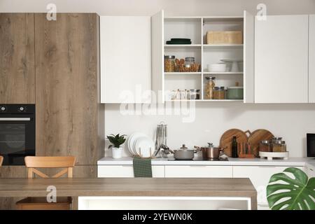 Interno di una cucina luminosa con ripiani, armadi e utensili Foto Stock