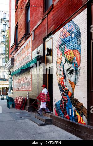 Colorato murale di audrey hepburn su un muro di mattoni in via dei gelsi, Little italy New york, persone che camminano in primo piano e un idrante del fuoco Foto Stock