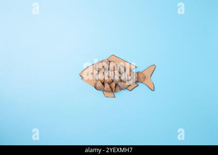 un'opera d'arte creativa simile a un pesce, realizzata con materiali naturali. Il corpo del pesce è realizzato con un pezzo di cartone tagliato a forma di A. Foto Stock