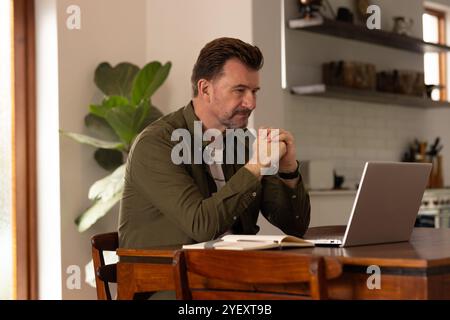 uomo anziano che lavora su un notebook a casa, concentrandosi sullo schermo con attenzione Foto Stock