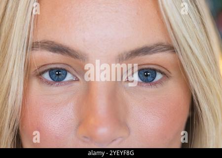 Primo piano degli occhi blu della donna e dei capelli biondi, che mostrano la bellezza naturale, a casa Foto Stock