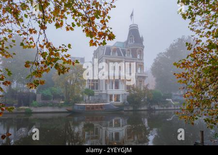 Una tranquilla mattinata d'autunno ad Amsterdam rivela uno splendido edificio storico avvolto dalla nebbia. Foto Stock