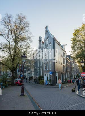 Amsterdam, 23 ottobre 2024, tra il fogliame dorato dell'autunno, i pedoni passeggiano lungo i canali iconici di Amsterdam, circondati da un'affascinante architettura secolare Foto Stock