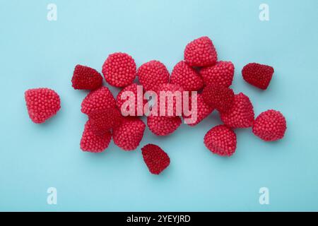 Dolci da masticare rossi sotto forma di bacche. Dolci sotto forma di lamponi su sfondo blu. Foto Stock