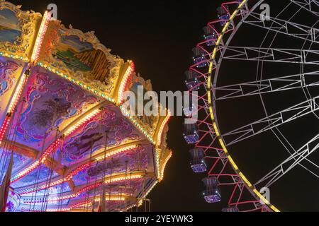 Un parco divertimenti notturno con giostra a catena illuminata e ruota panoramica, Europa Rad, giostre, volo a onde, Cannstatter Wasen, festa popolare, Bad Cannstatt, Foto Stock