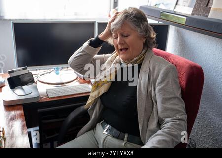 donna matura dai capelli grigi con mal di testa Foto Stock