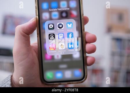 Tenere a mano un telefono cellulare su cui è possibile vedere i logo dei vari provider di social media Foto Stock