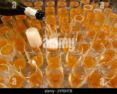 Vista panoramica completa del prosecco versato in bicchieri con purea di pesca per preparare cocktail bellini Foto Stock