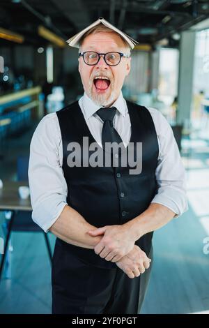 Vecchio emotivo in occhiali con un taccuino in ufficio. Un vecchio uomo d'affari si aggrava sulla fronte. Foto Stock