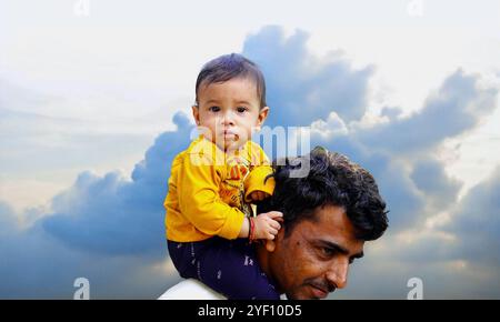 Padre maturo che fa un giro in piggyback a un figlio piccolo sullo sfondo dello studio. Festa dei padri. Ritratto di un figlio felice sorridente seduto sulle spalle dei padri e l Foto Stock