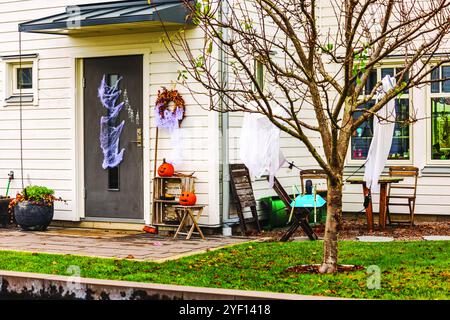 Decorazioni di Halloween sul portico con zucche intagliate, ragnatele sulla porta e figure spettrali appese ai rami. Foto Stock