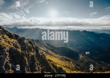 Il sole luminoso splende magnificamente attraverso le soffici nuvole che si innalzano sulle montagne lontane, creando una scena pittoresca Foto Stock