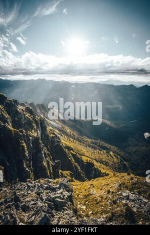 Il sole luminoso splende magnificamente attraverso le soffici nuvole che si innalzano sulle montagne lontane, creando una scena pittoresca Foto Stock