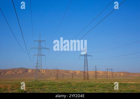 Tralicci elettrici che trasportano linee elettriche aeree attraverso la riserva storica e culturale statale di Gobustan a Gobustan, Azerbaigian Foto Stock