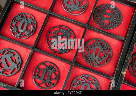 Vari disegni di guardie di spada giapponesi in metallo chiamate "tsuba" in vendita in un mercato a Seki City, prefettura di Gifu, Giappone. Foto Stock