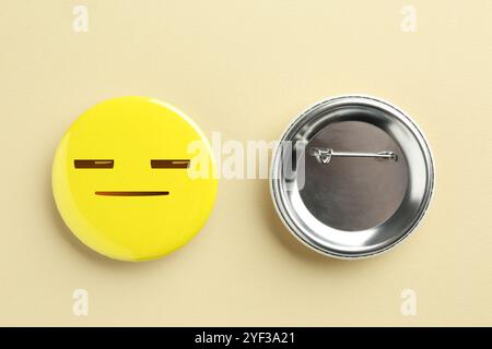 Badge su sfondo beige. Uno con la faccia diffidente o assonnata Foto Stock
