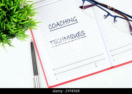 Il concetto di business e sviluppo. Testo concettuale, frasi, TECNICHE DI COACHING delle parole su un foglio vuoto di un blocco appunti aperto. Foto Stock
