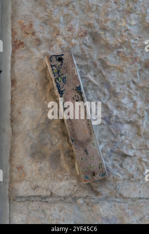 Una mezuzah affissa su un muro di pietra all'ingresso di una casa a Gerusalemme, Israele. Una mezuzah è un rotolo contenente versi scritturali che ricordano gli ebrei Foto Stock