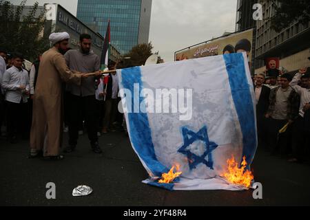 Teheran, Iran. 3 novembre 2024. Un chierico iraniano brucia una bandiera Isreal durante una manifestazione anti-americana che celebra il 45° anniversario dell'acquisizione dell'ambasciata americana davanti all'ex edificio dell'ambasciata di Teheran. Il 4 novembre 1979, studenti iraniani sequestrarono l'ambasciata degli Stati Uniti a Teheran, tenendo in ostaggio oltre 50 diplomatici e guardie americane per 444 giorni. Crediti: ZUMA Press, Inc Crediti: ZUMA Press, Inc./Alamy Live News Foto Stock