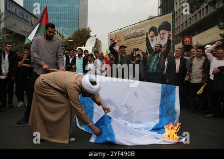 Teheran, Iran. 3 novembre 2024. Un chierico iraniano brucia una bandiera Isreal durante una manifestazione anti-americana che celebra il 45° anniversario dell'acquisizione dell'ambasciata americana davanti all'ex edificio dell'ambasciata di Teheran. Il 4 novembre 1979, studenti iraniani sequestrarono l'ambasciata degli Stati Uniti a Teheran, tenendo in ostaggio oltre 50 diplomatici e guardie americane per 444 giorni. Crediti: ZUMA Press, Inc Crediti: ZUMA Press, Inc./Alamy Live News Foto Stock