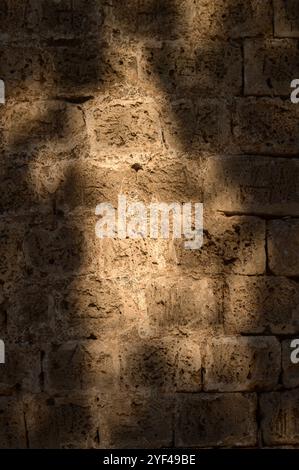 Ombre morbide giocano su un'aspra parete di pietra, catturando un momento di tranquillità durante la luce della sera. Foto Stock