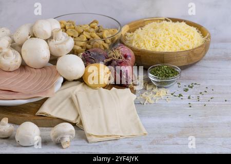 Vari ingredienti per cucinare, tra cui funghi, formaggio, cipolla e prosciutto su un tavolo Foto Stock