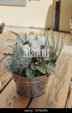 Composizione floreale. Bouquet di piante secche, fiori o foglie in un piccolo vaso a secchio su un vecchio tavolo di legno Foto Stock