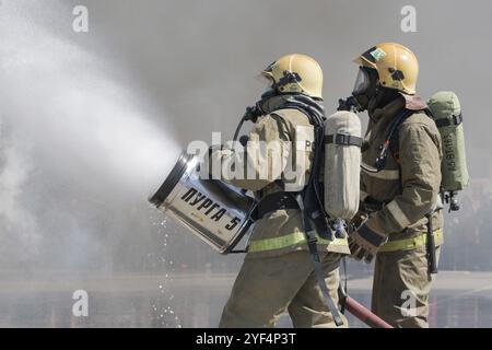 I vigili del fuoco estinguono il fuoco dal tubo antincendio, utilizzando un cilindro in schiuma d'acqua antincendio con schiuma meccanica ad aria durante le vacanze professionali dei vigili del fuoco Foto Stock