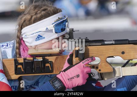 La biatleta di San Pietroburgo Shishkina Vlada nel poligono di tiro. Sportiva biatleta che mira, fucile che spara in posizione prona. Gara di biathlon junior Foto Stock