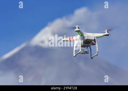 Drone volante quadricottero UAV fotografia aerea in cielo su sfondo vulcano eruzione, picco del monte eruzione ceneri, gas dal cratere attivo. Concentrati sul fronte Foto Stock