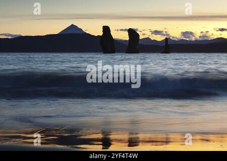 Uno splendido tramonto, pittoresca vista delle tre rocce dei Fratelli nella Baia di Avacha e del Vulcano Viluchinsky all'orizzonte. Oceano Pacifico, Estremo Oriente russo, Ka Foto Stock