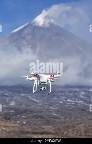 Volo drone quadricottero UAV fotografia aerea in cielo sullo sfondo dell'eruzione vulcanica, picco di montagna che erutta ceneri, plume gas vulcanico da attivo Foto Stock