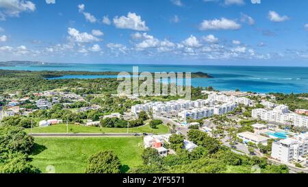 Vista aerea vicino alla spiaggia Seven Seas a Fajardo, Porto Rico, con vegetazione lussureggiante, zone residenziali costiere, oceano caraibico e cielo blu Foto Stock