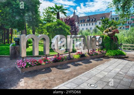 MERANO, ITALIA - 22 LUGLIO 2024: Cartello con il nome della città di Merano in piedi in un parco pubblico circondato da fiori colorati in fiore in una soleggiata giornata estiva, South Ty Foto Stock